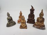 trois petites statues de bouddhas sont assises sur une surface blanche
