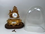 a gold clock under a glass dome on a table