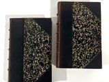 deux livres noirs et dorés posés l'un à côté de l'autre sur une surface blanche