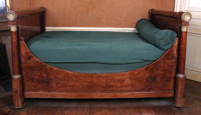 un lit en bois recouvert d'un couvre-lit vert, dans une chambre