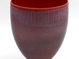 a close up of a red bowl on a white surface