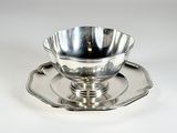 une tasse et une soucoupe en argent posées sur un plateau en argent