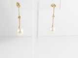 a pair of pearl and gold earrings on a stand