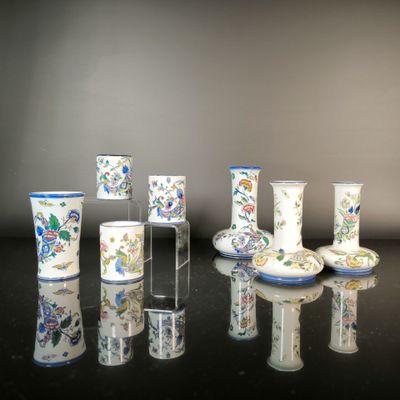 seven vases sitting on a table with a black background