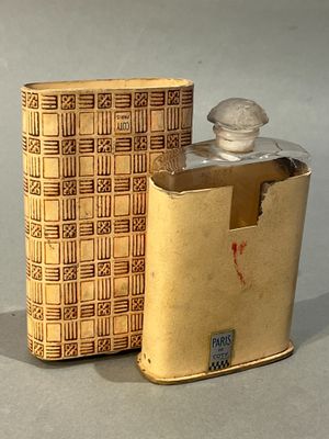 une flasque en or et une boîte posées sur une table