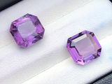 deux pierres précieuses violettes dans une boîte noire posée sur une surface blanche