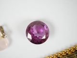 an image of a purple stone sitting on top of a gold chain