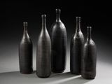 quatre bouteilles noires sont alignées sur une surface blanche