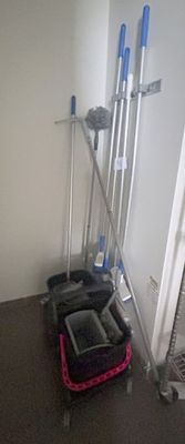 a luggage bag and brooms on the floor in a room