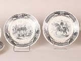 four plates with black and white designs are lined up on a table