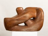 wooden sculpture of a man and a woman on a white pedestal