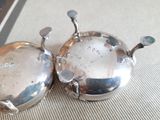 two silver dishes sitting on a table with a knife