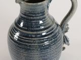 a blue vase with a handle on a white surface