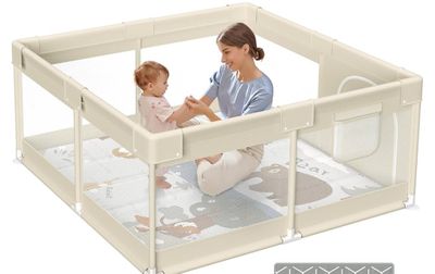 a woman holding a baby inside of a baby playpen