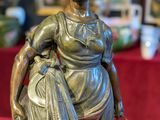 bronze statue of a woman carrying a basket on a red table