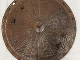 une plaque métallique sur laquelle est représenté un motif en rayons de soleil