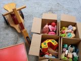 une boîte remplie de jouets posée par terre à côté d'un cheval en bois