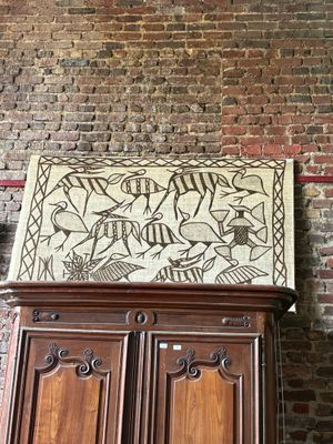 a cabinet with a painting on top of it in front of a brick wall