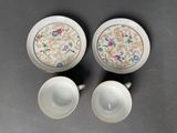 two cups and saucers with floral designs on them on a table