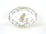 une assiette décorée d'un oiseau, posée sur un socle