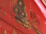 a close up of a red painted cabinet with flowers on it