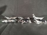 three silver figurines sitting on top of a black cloth