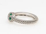 a close up of a diamond and emerald ring on a white surface
