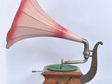 un gramophone rose et vert posé sur un socle en bois