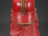 a red vase with a leaf on top of it on a black surface