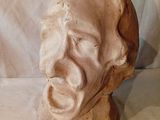une sculpture en argile représentant le visage d'un homme, posée sur un tissu blanc