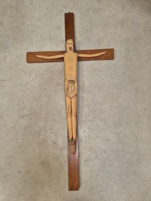 une croix en bois posée par terre, sur laquelle se trouve un homme