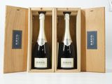 deux bouteilles de champagne dans un coffret en bois, posées sur une surface blanche