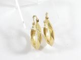 une paire de boucles d'oreilles en or sur une surface blanche