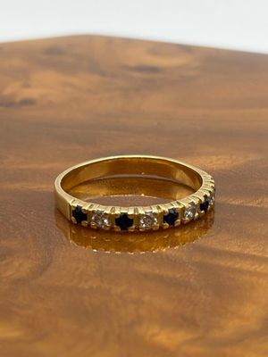 bague en or jaune sertie de diamants noirs et blancs sur un support en bois