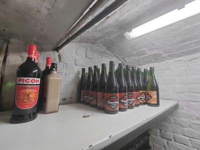 Plusieurs bouteilles de bière sont alignées sur une étagère dans une pièce