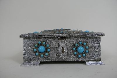 une boîte en argent ornée de pierres turquoise, posée sur une table