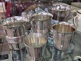 une table en verre sur laquelle sont posées des tasses en argent, dans un magasin
