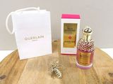 a bottle of guerlain perfume next to a bag on a wooden table