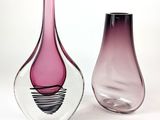 two glass vases sitting next to each other on a white surface