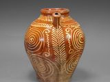 a brown vase with white designs on it on a gray surface