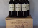quatre bouteilles de vin rouge dans un coffret en bois posé sur une table