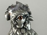 a silver and gold vase with a rooster head on it