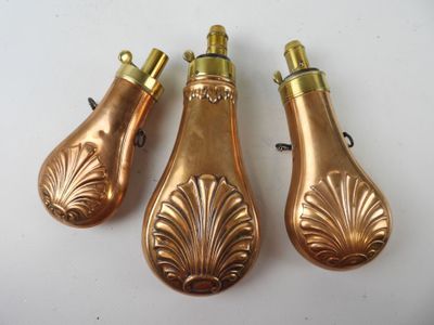trois briquets anciens en laiton posés sur une surface blanche