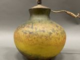 a yellow and brown vase with a rope on top of it