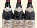 trois bouteilles de vin rouge posées l'une à côté de l'autre sur une surface blanche