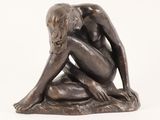 statue of a woman sitting on a rock with her hands on her knees