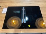 une assiette en verre noir sur laquelle sont posées deux bougies jaunes