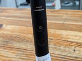 une brosse à dents électrique noire posée sur une table en bois