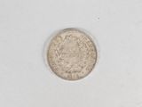 an old silver coin sitting on top of a white surface