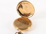 a gold pocket watch sitting on a white surface